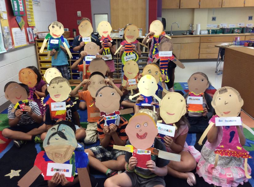 Photo of students covering their faces with self-portraits.